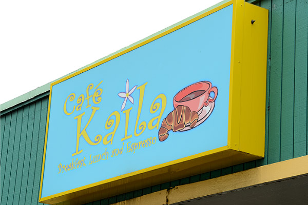 Image of the sign of Cafe Kaila which has a blue background with pink lettering