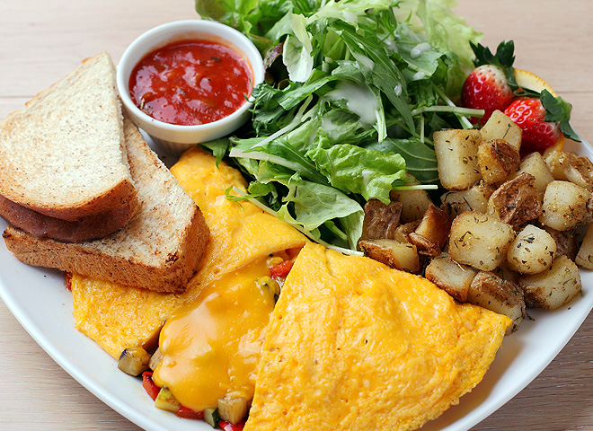 Image of scrambled egg omelette with potatoes and green salad.