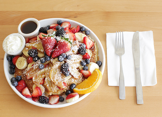 Stack of pancakes with lots of strawberries, blueberries, and banana